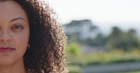 Half-face portrait of african american woman with backlit curly hair and gold hoop earring