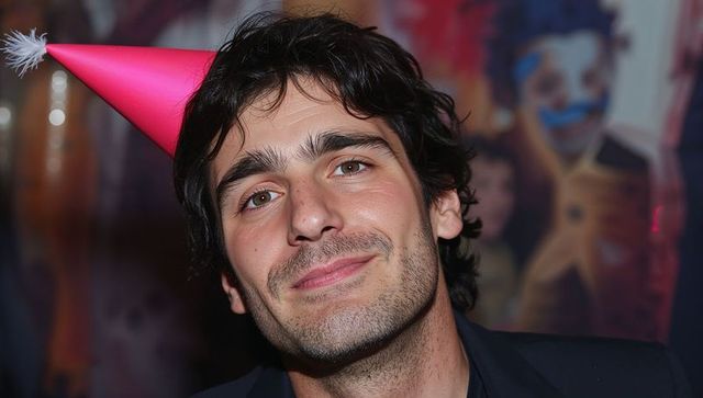 Smiling man wearing pink party hat celebrating at colorful event portrait close-up