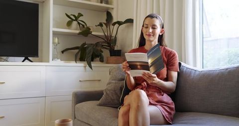 Woman Relaxing on Sofa with Book in Modern Living Room