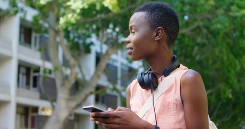 Young Woman with Smartphone and Headphones Outdoors in Urban Environment