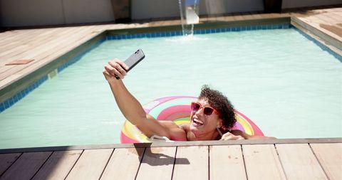 Man enjoying pool day on colorful float taking selfie