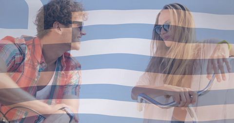 Smiling couple cycling with greek flag overlay showing vacation fun