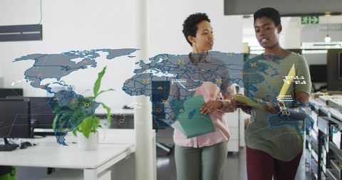 Diverse Businesswomen Analyzing Documents with World Map Projection