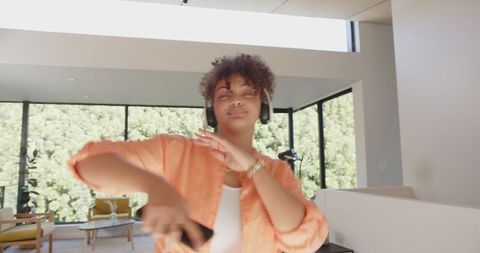 Young Woman Dancing with Headphones and Smartphone in Modern Living Room
