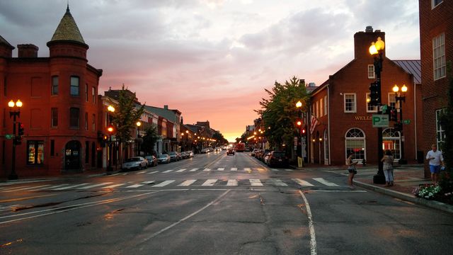 Sunset on an empty city street lined with historic buildings reflecting warm light from street lamps. Perfect for depicting peaceful evening urban scenes, illustrating architectural beauty, travel destinations, or romantic, serene settings. Ideal for travel blogs, urban studies, and city lifestyle content.