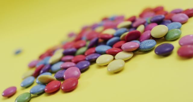 Image of multicoloured lentils on yellow background. colourful fun food, candy, snacks and sweets concept.