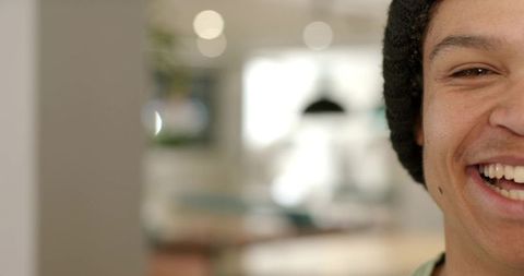 Closeup smiling african american man wearing beanie in cozy cafe with warm bokeh