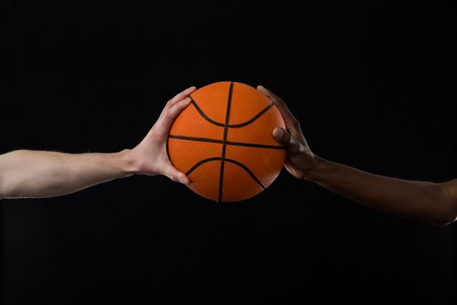 Close-up competitors holding basketball against black background