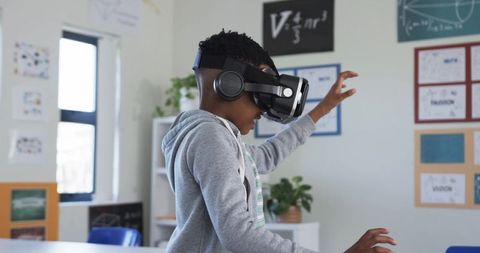 African American Teen Exploring Virtual Reality Wearing VR Headset in Classroom