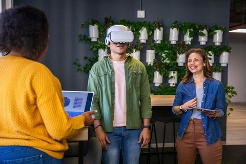 Diverse team testing VR headset during collaborative demo in modern coworking office lounge