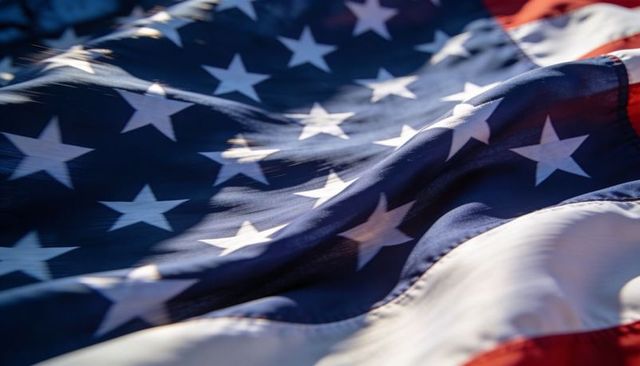 Waving american flag close-up showing stars and stripes sunlit fabric texture for holidays