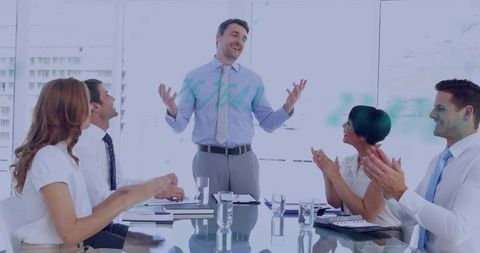 Male manager presenting to applauding team around glass conference table in modern boardroom