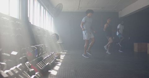 Men jumping rope together in gym with weights rack