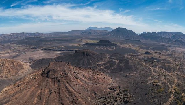 Aerial panoramic of eroded cinder cones and basalt lava fields on arid volcanic plateau