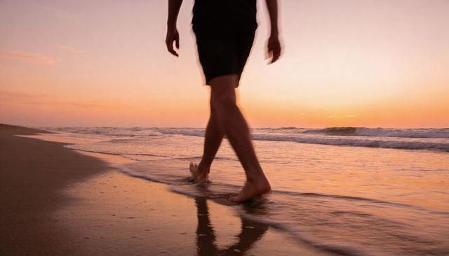 Sunset Beach Walk Man Walking Barefoot Along Shoreline Leaving Footprints on Wet Sand
