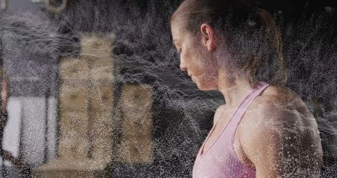 Female athlete training in gym with chalk dust swirl