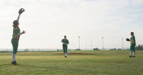 Diverse female softball team practicing on green field
