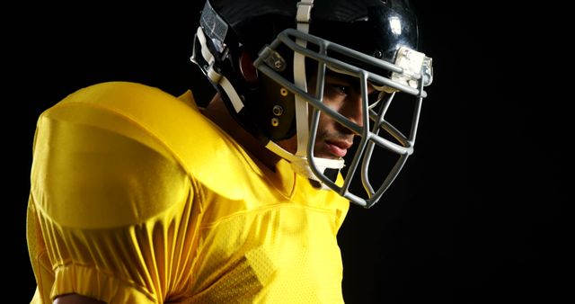 Focused Football Player in Yellow Jersey Wearing Helmet Lit Dramatically - Download Free Stock Images Pikwizard.com