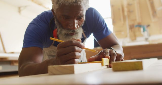 African american male carpenter making pencil markings on wooden plank. carpentry, craftsmanship and handwork concept