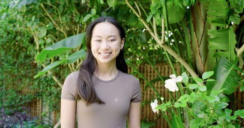 Smiling Woman Relaxing in Lush Tropical Backyard