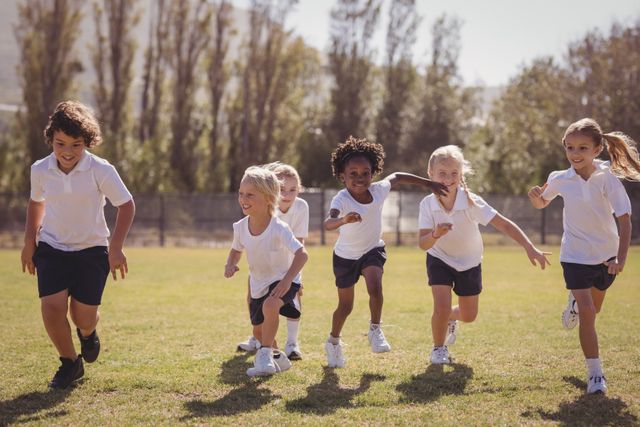 Group of schoolchildren running together in a park on a sunny day. Ideal for use in educational materials, advertisements for children's activities, fitness programs, or community events promoting outdoor play and exercise.