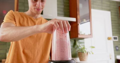 Happy Man Blending Fruit Smoothie in Modern Kitchen