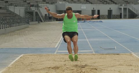 Athletic male long jumper in action on track field