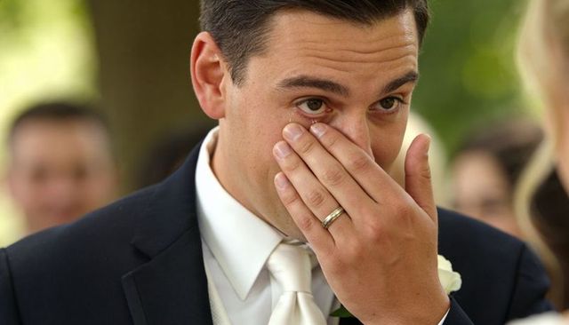 Emotional groom wiping tears during outdoor wedding vow exchange sunlit close-up portrait