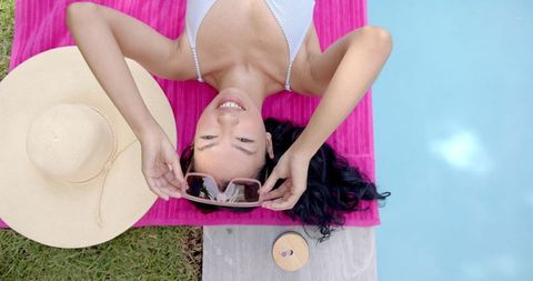 Woman Relaxing Poolside with Sun Hat and Sunglasses