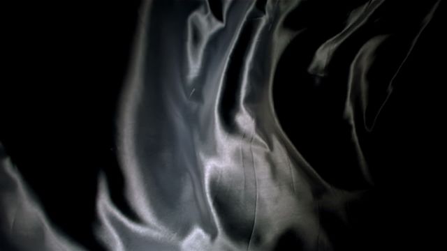 Black silk fabric gracefully flowing with a glossy texture creates a sense of luxury and sophistication. Ideal for fashion projects, textile designs, or promotional materials emphasizing elegance and style. Can be used as a background for haute couture themes or to highlight products related to luxurious materials.