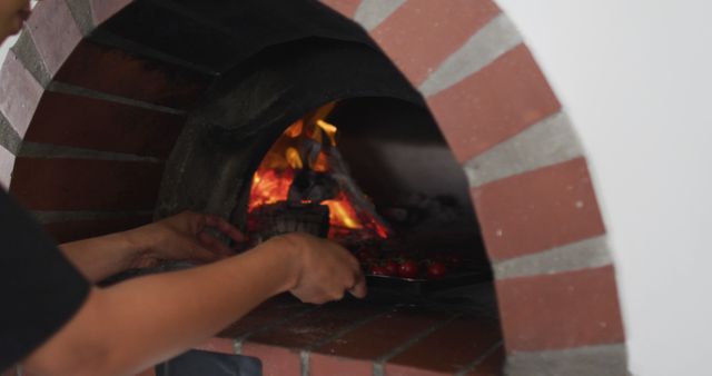 Hands placing pizza in brick wood-fired oven, depicting authentic Italian cooking. Ideal for use in promotions for pizzerias, Italian restaurants, culinary blogs, and cooking classes focused on traditional methods. Conveys theme of authenticity, tradition, and culinary expertise.