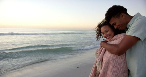 Couple Embracing Sunset on Beach Wrapped in Blanket