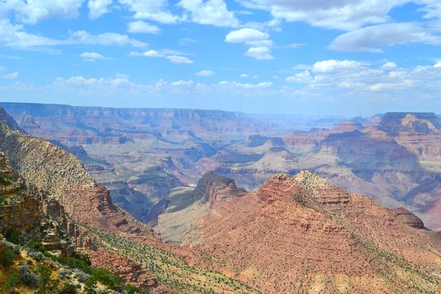 Stunning view of Grand Canyon with clear skies displaying a majestic landscape of layered rock formations and expansive desert. Perfect for travel brochures, nature blogs, educational materials, or wallpapers.