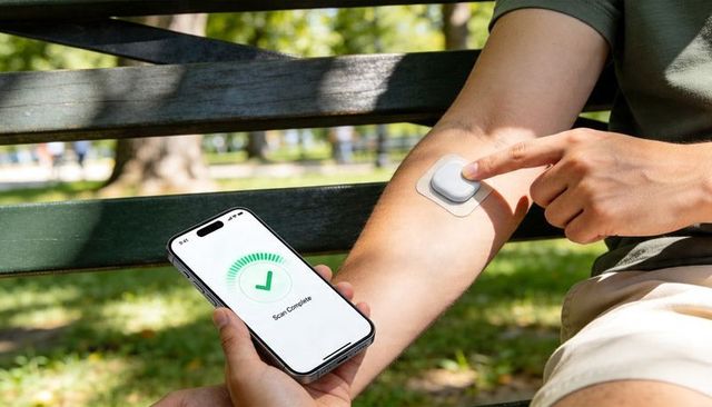 Man pressing smart wearable patch on arm while smartphone app shows scan complete in park