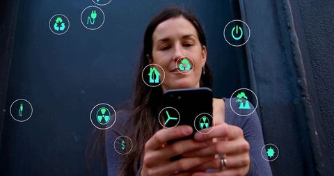 Woman holding smartphone while viewing floating sustainability and energy icons overlay