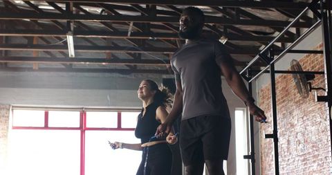 Diverse fitness partners skipping ropes in industrial gym environment