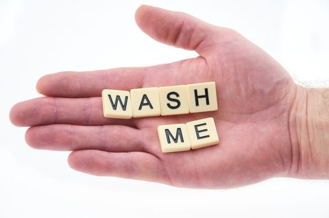 Scrabble tiles spelling 'wash me' on open hand