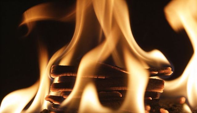 Closeup stacked bark sticks burning with glowing orange flames and warm ember light