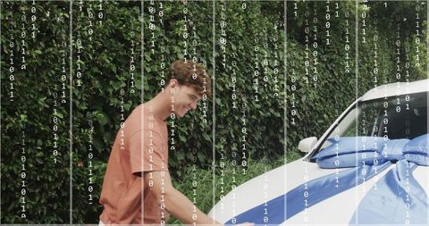 Young man placing blue bow on white car in driveway with digital binary overlay