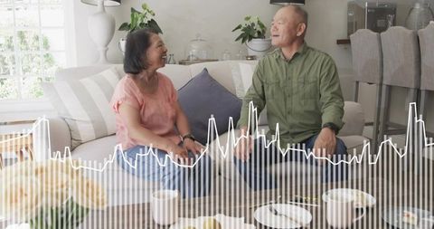Mature couple chatting and smiling on striped sofa with waveform overlay in cozy living room