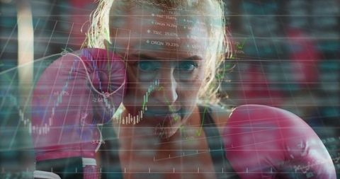 Female boxer training with pink gloves facing camera with financial charts overlay