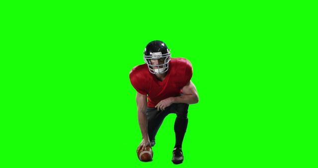 American football player kneeling and holding football against green screen background. Useful for creating custom sports graphics, promotional materials, football-themed advertisements, video editing, and educational content related to sports training or tactics.