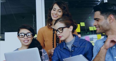 Young professionals collaborating around laptop and tablet in modern coworking space