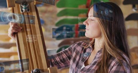 Woman inspecting striped wood longboard with augmented reality overlays in skate shop