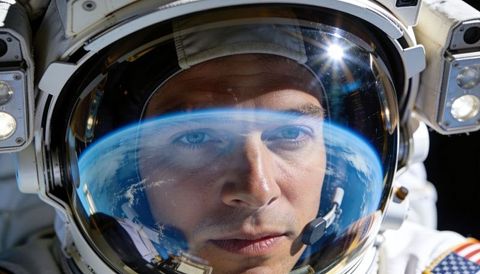 Astronaut gazing through visor reflecting earth horizon while communicating during spacewalk