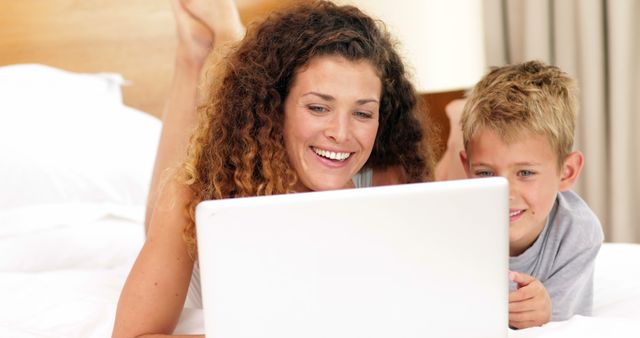 Smiling Mother and Son Using Laptop on Bed - Download Free Stock Images Pikwizard.com