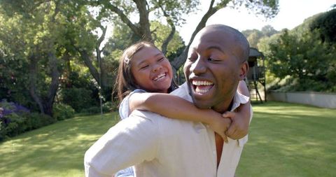 Father and Daughter Enjoying Playful Piggyback Ride Outdoors