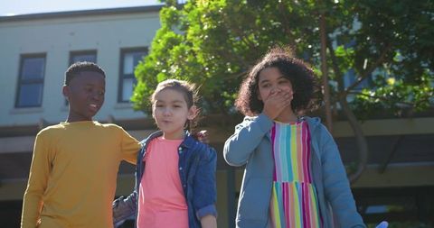 Multicultural kids standing on school steps reacting with surprise and laughter