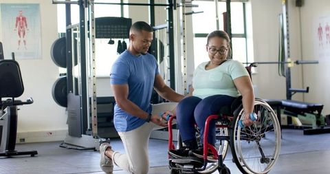 Fitness Trainer Assisting Woman in Wheelchair with Workout