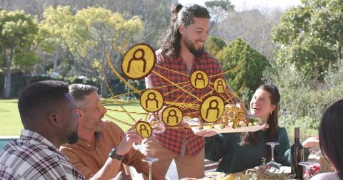 Serving platter while digital social network icons connecting friends at outdoor gathering